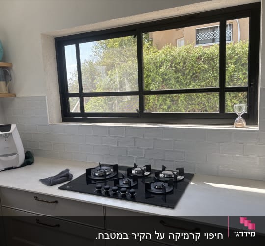 מטבח מעוצב עם משטח עבודה, כיריים בנויות וחיפוי קיר בבריקים בהירים